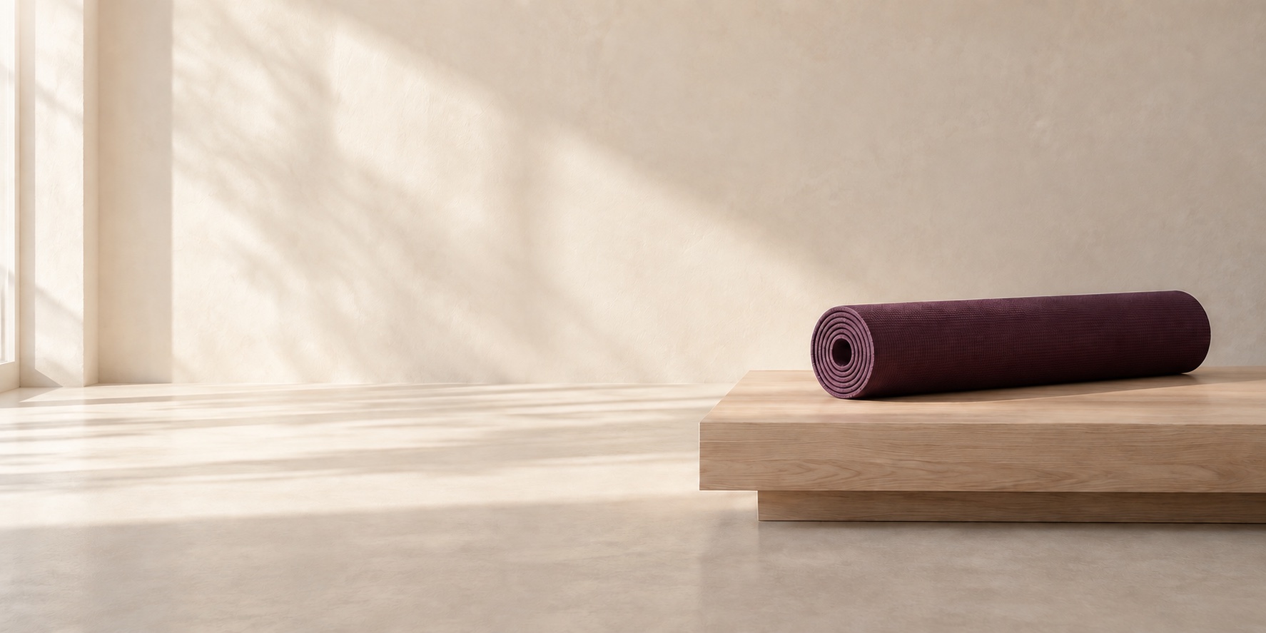 En yogamatta, massageolja och vikta handdukar i mjukt morgonljus